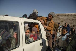 As many of 30 people climb into one truck to drive three hours to the border with Pakistan, with single men in the back and families and children in the front, in Zaranj, Afghanistan, Nov. 19, 2021. (Kiana Hayeri/The New York Times)