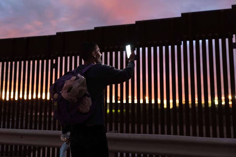Migrante venezuelano fala com a esposa por chamada de vídeo após conseguir cruzar a fronteira do México com os Estados Unidos na cidade de Yuma, no Arizona
