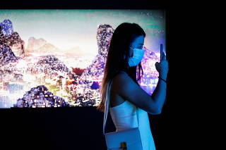 FILE PHOTO: Visitor takes a photo in front of a video installation which will be converted into NFTs and auctioned online at Sotheby's, in Hong Kong