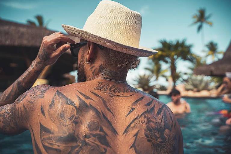 Tatuagens nas costas de Neymar feitas à época de seu 28º aniversário; ele está de costas na foto e usa um chapéu de palha