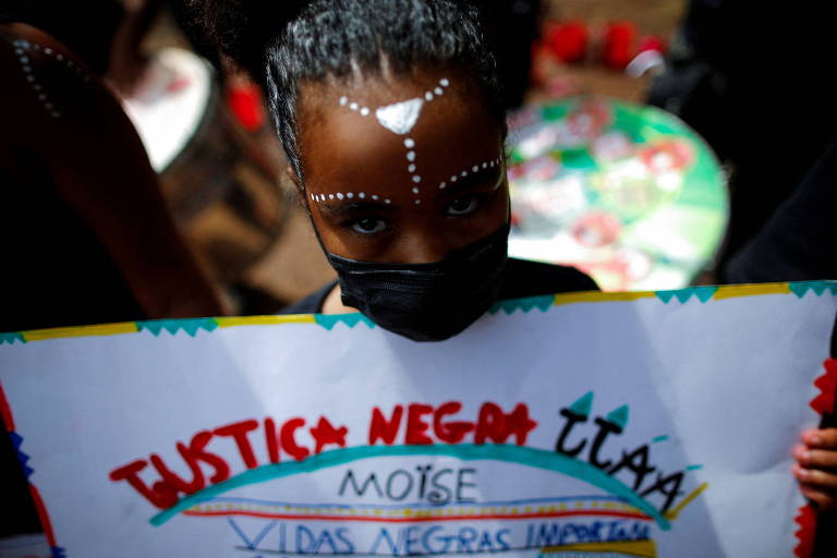 Meninas negra com mascara e cartaz em que se lê Justiça Negra e Vidas Negras Importam