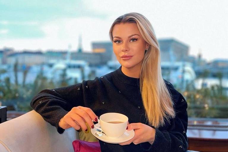 Fotografia de uma mulher loira tomando café num terraço