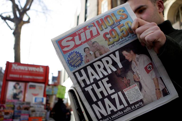 Britânico lê o jornal "The Sun", que tem na capa a fotografia do príncipe Harry, vestindo um uniforme nazista durante uma festa à fantasia