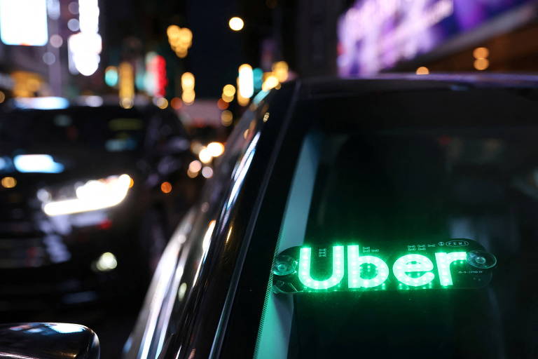 Carro preto com painel luminoso escrito Uber, em verde 