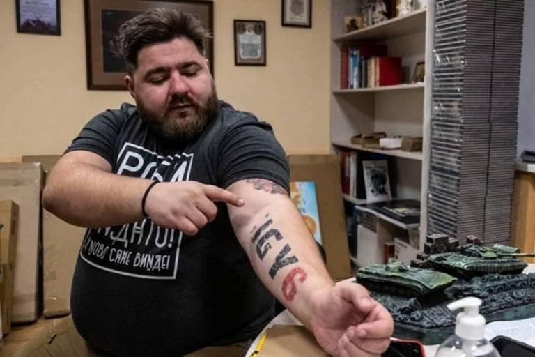 O psicólogo militar Andrii Kozinchuk mostra tatuagem que diz: 'Estou aqui te apoiando'