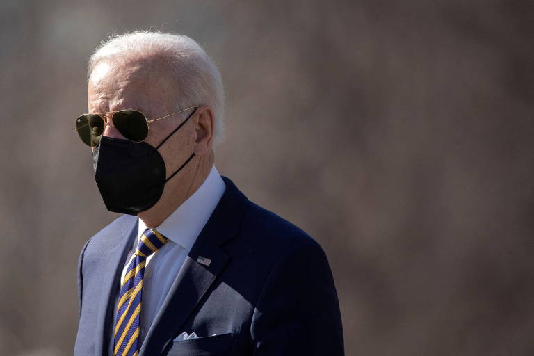 O presidente dos EUA, Joe Biden, na Casa Branca; ele veste camisa, paletó e gravata e usa óculos escuros e máscara de proteção contra o coronavírus