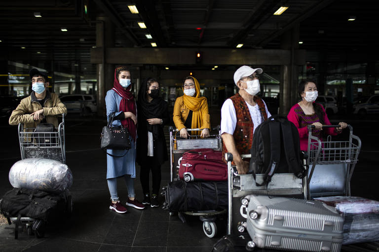 A família carrega a bagagem na saída do aeroporto de Guarulhos