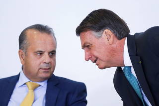 Brazil's Regional Development Minister Rogerio Marinho listens to President Jair Bolsonaro during a ceremony at the Planalto Palace, in Brasilia