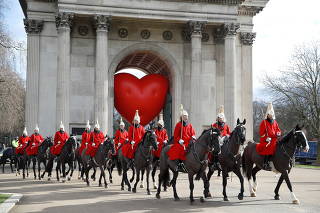 Members of the Household Cavalry walk past Wellington Arch and a large inflatable heart, on Valentine's Day in London