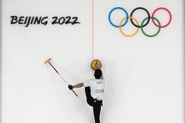 O chinês Ling Ahi segura a pedra do curling durante prova das Olimpíadas de Pequim-2022