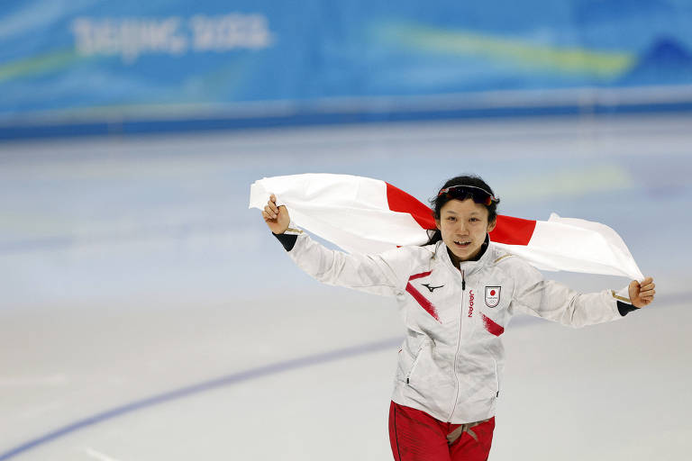 Miho Takagi celebra com a bandeira do Japão após conquistar o ouro na patinação de velocidade
