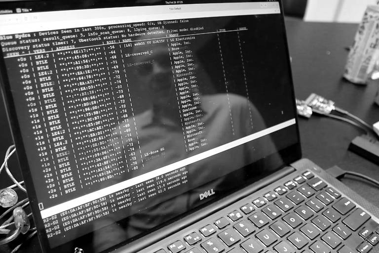 Reflexo do hacker é visto à frente de tela escura do computador, com informações de bluetooth na região