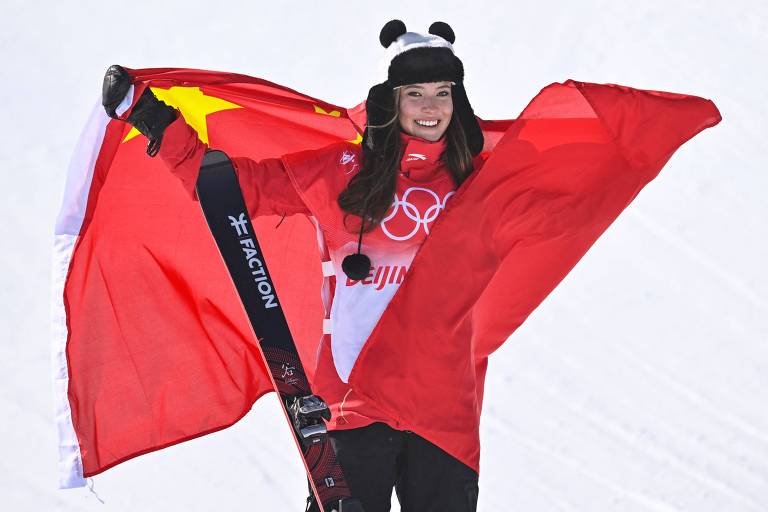 Eileen Gu celebra o ouro no halfpipe com a bandeira da China
