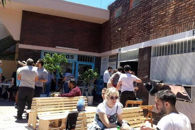 Clientes ser reúnem em mesas de espaço comum no Pony Pizza, na Pasaje Echeverría, em Belgrano