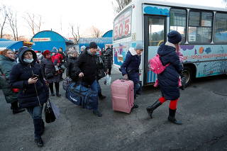 People walk to board a bus during the evacuation of local residents to Russia, in Donetsk