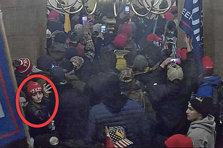 Multidão entra por meio de uma porta; mulher com um gorro vermelho é identificada com marcação em vermelho
