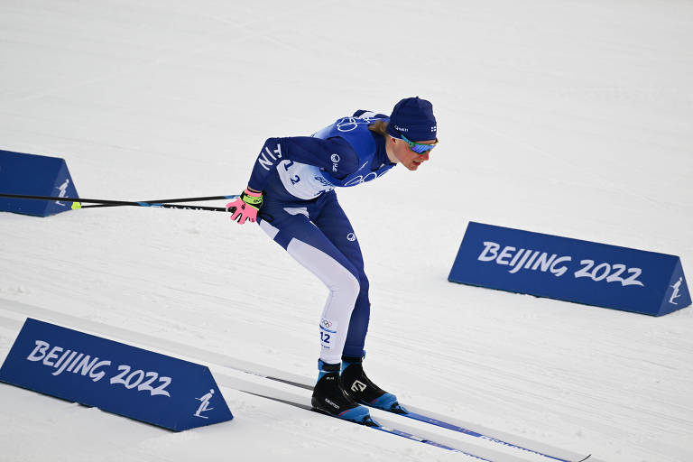 homem magro com uniforme azul e branco esquiando durante corrida