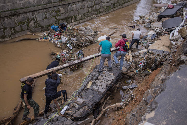 Voluntários entram em rio para encontrar jovem que desapareceu em ônibus de Petrópolis