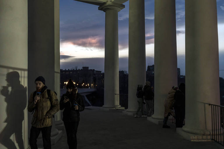 Pessoas observam o pôr do sol em Odessa, por meio de grandes colunas brancas 