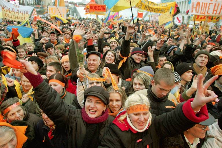Simpatizantes de Viktor Yushchenko carregam bandeiras e faixas e fazem o sinal da vitória em manifestação em Kiev
