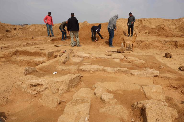 Trabalhadores palestinos escavam o recém-descoberto cemitério da era romana com sepulturas ornamentadas em Beit Lahia, no norte da Faixa de Gaza