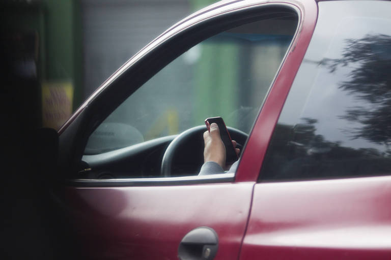 Motorista digita no telefone celular enquanto dirige em São Paulo
