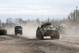 Military vehicles drive along a street in Armyansk