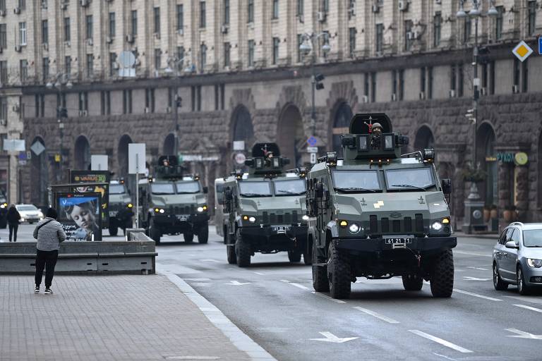 Carros de exército passando em fila em rua 