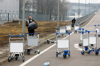 A person walks past luggage carts at Boryspil International Airport after Russian President Vladimir Putin authorized a military operation in eastern Ukraine