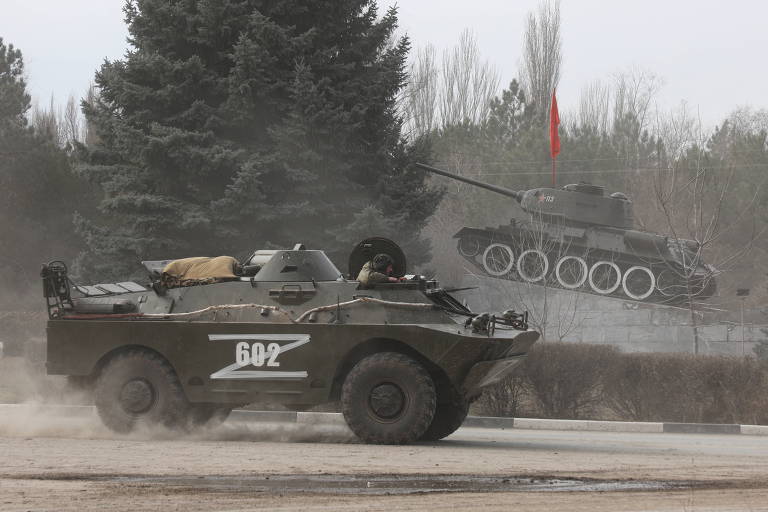 Blindado russo marcado com a letra 'Z' passa por monumento com tanque T-34 da Segunda Guerra na Crimeia, rumo à Ucrânia