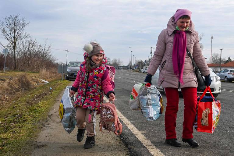 Muitos estão atravessando a pé, pelas estradas. Na imagem, uma mãe e sua filha caminham em direção à fronteira com a Hungria, para a cidade de Beregsurany