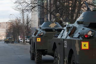 Ukrainian service members are seen atop of armoured personal carriers in Kyiv