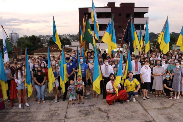 grupo de pessoas com bandeiras amarela e azul e roupas típicas da Ucrânia
