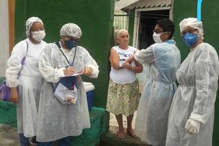 Agente comunitária de saúde Terezinha Gomes de Almeida (à direita, de luva) visita família na periferia de Manaus