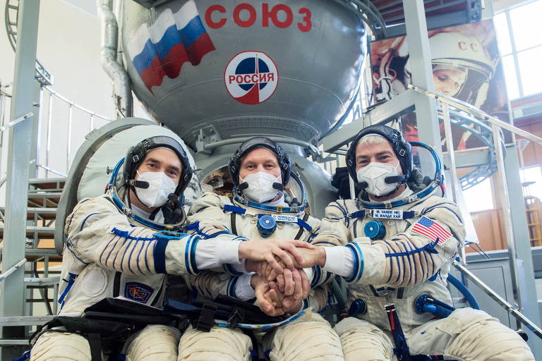 Astronauta e cosmonautas em frente a uma nave