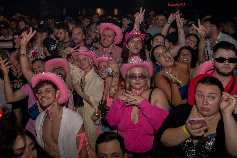Foto mostra pista de dança lotada. Grupo de foliões usa chapéu de caubói rosa