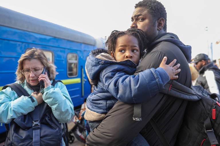 Pai espera com a filha na estação de trem de Kiev na quinta-feira, primeiro dia da invasão russa