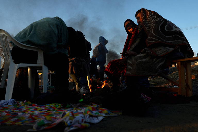 Refugiados enfrentam o frio com fogueira em um campo instalado no posto de fronteira em Medyka, Polônia