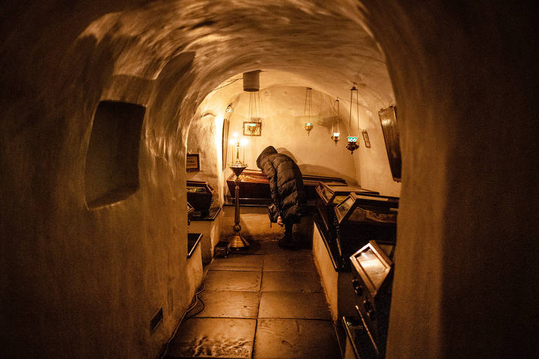 Uma mulher beija o caixão de um santo ortodoxo oriental nas catacumbas abaixo do Mosteiro das Cavernas, em Kiev