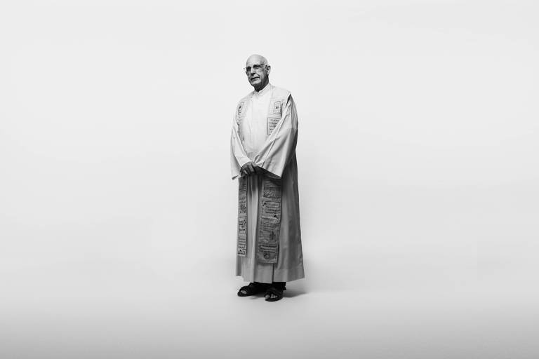 Vestido com túnica, padre Julio é retratado em fundo branco