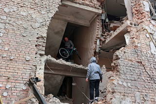 A man carries a bicycle out of a residential building destroyed by recent shelling in Irpin