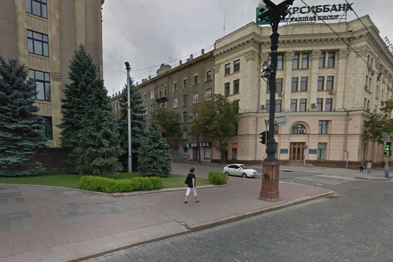 Captura de tela pelo Google Maps de esquina de um prédio do governo em Kharkiv; há uma mulher andando, um carro parado, algumas árvores e o céu está nublado