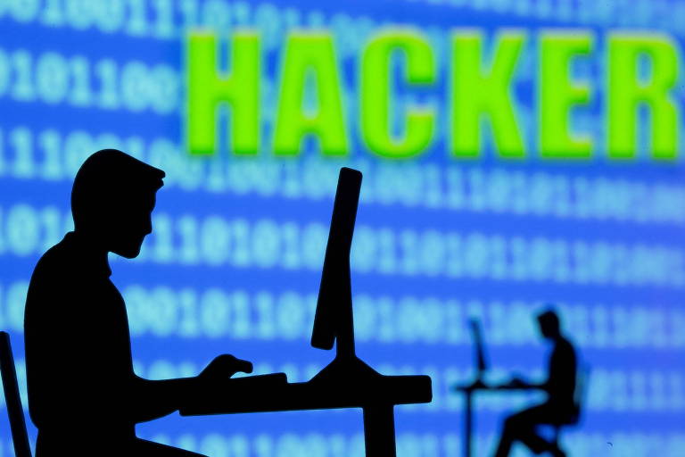 Silhueta de homem em frente a tela com palavra hacker
