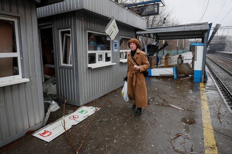 Uma mulher é vista perto de um prédio da administração ferroviária da Ucrânia danificado por bombardeios recentes perto de uma estação de trem central em Kiev
