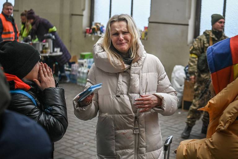 Uma mulher chora enquanto tenta embarcar em um trem gratuito para a Polônia em uma estação de trem em Lviv, no oeste da Ucrânia