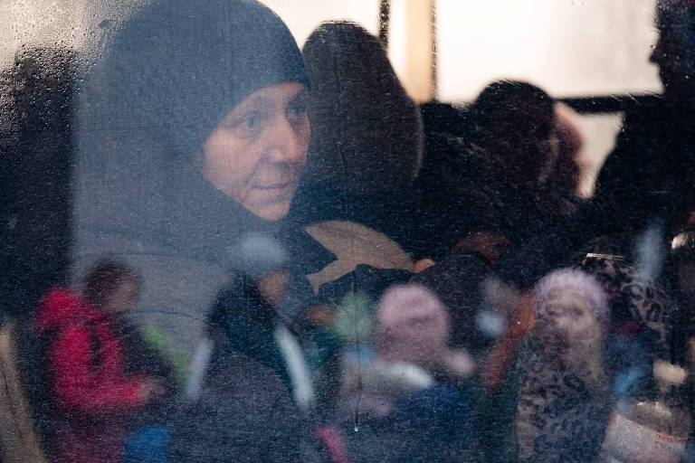 Uma mulher aguarda dentro de um ônibus enquanto os evacuados da cidade de Irpin chegam em Kiev, Ucrânia