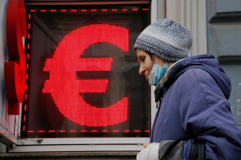 Mulher caminha diante de painel que mostra símbolo do euro, em São Petersburgo, na Rússia