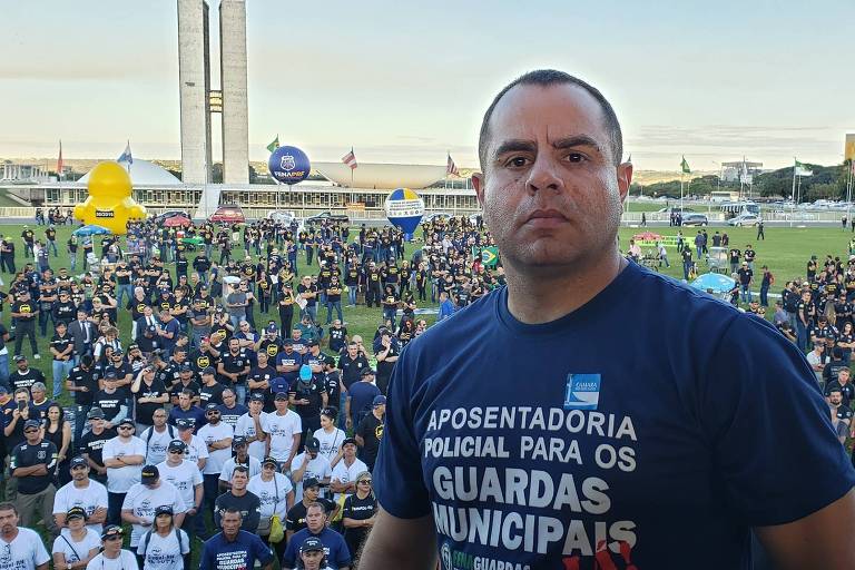 Homem com camiseta azul em frente à uma multidão em Brasília