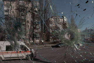 An ambulance is seen through the damaged window of a vehicle hit by bullets in Kyiv