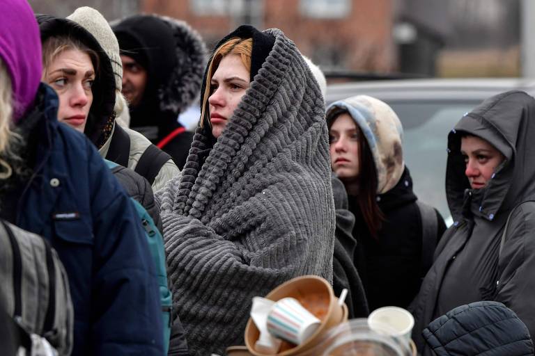 Refugiadas ucranianas esperam ônibus após atravessarem a fronteira com a Polônia